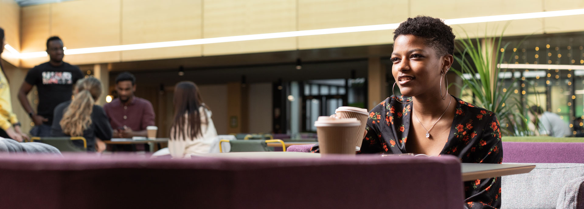 A student sitting in the atrium with a coffee