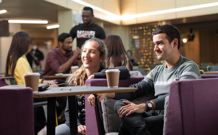 Students sitting and talking at a table in Campus Central Atrium