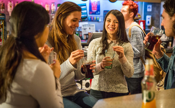 A group of happy students drinking and laughing in the student union