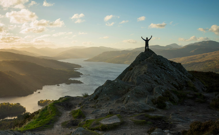 A walker posing on the summit of Ben Aan