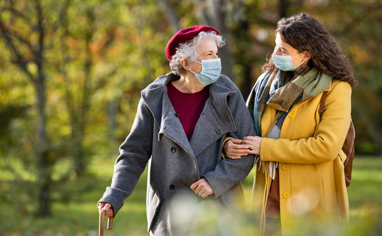 A young woman and old woman walking arm-in-arm