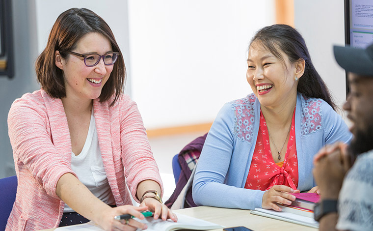 Students talking and laughing, sat down in classroom