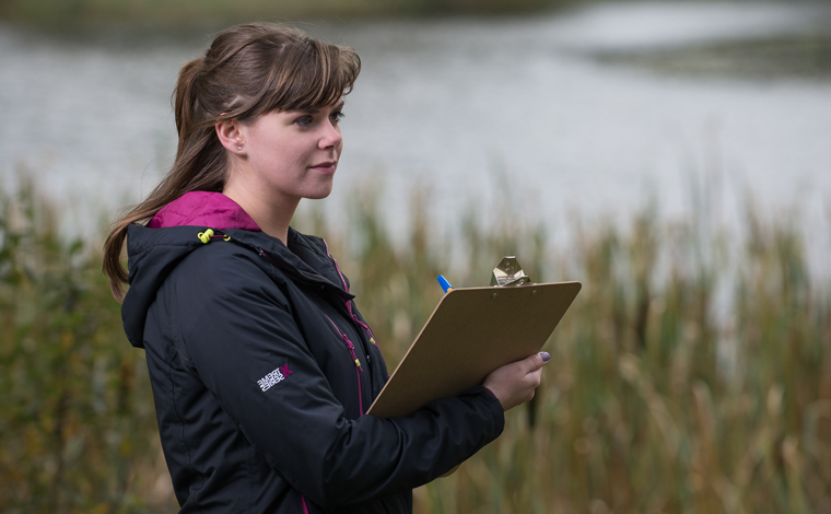 student outdoors with clipboard