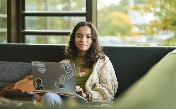 Student sitting in campus central using a laptop