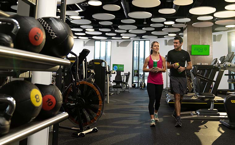 Two students walking through the gym