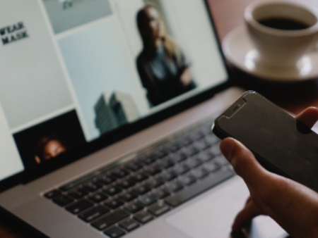 Person holding phone on computer