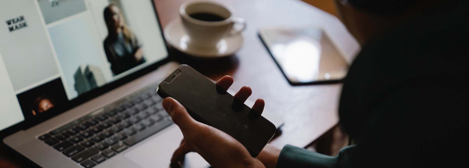 Person holding phone on computer