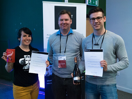 one woman and two men posing with a box of chocolates and certificates