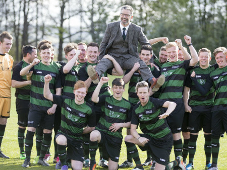 group of male football players holding up their coach on their shoulders