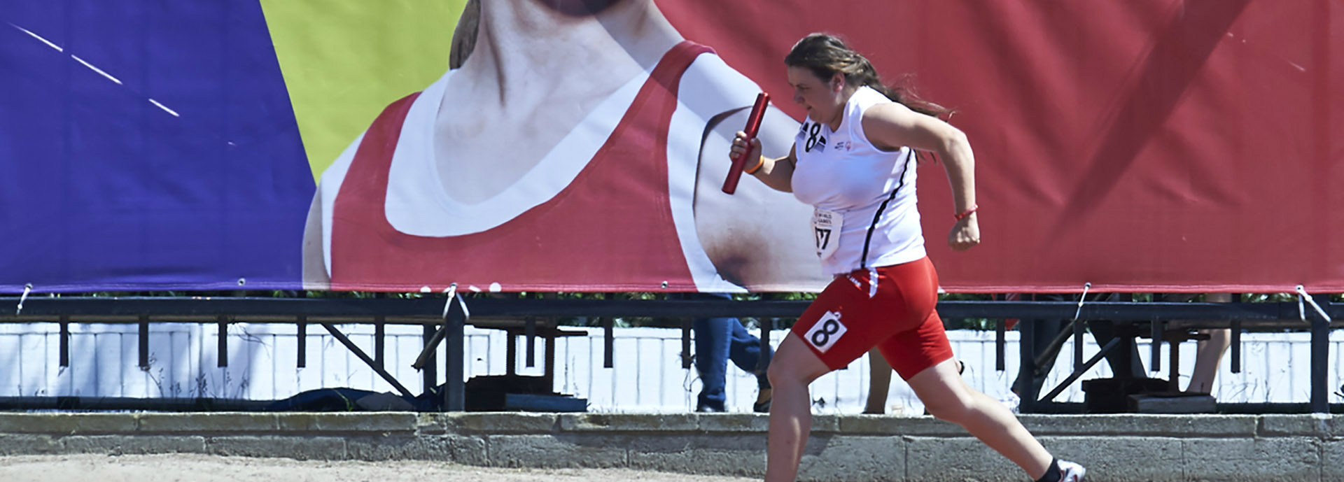 Special Olympics female athlete running with relay baton