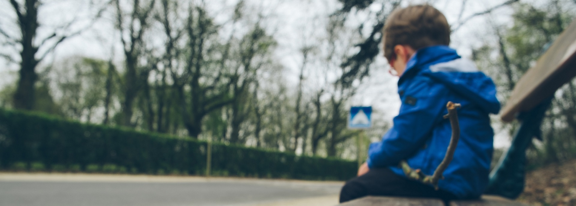 young child sitting alone on a roadside bench