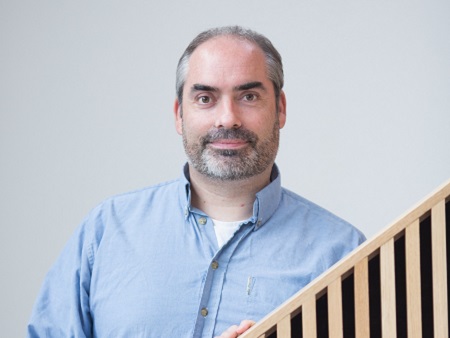 Head and shoulders shot of man with beard in blue shirt