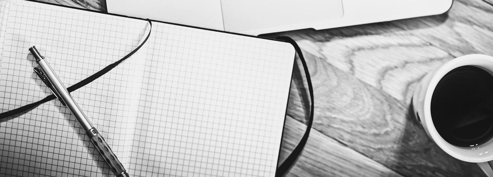 An open notebook next to a cup of coffee on a table