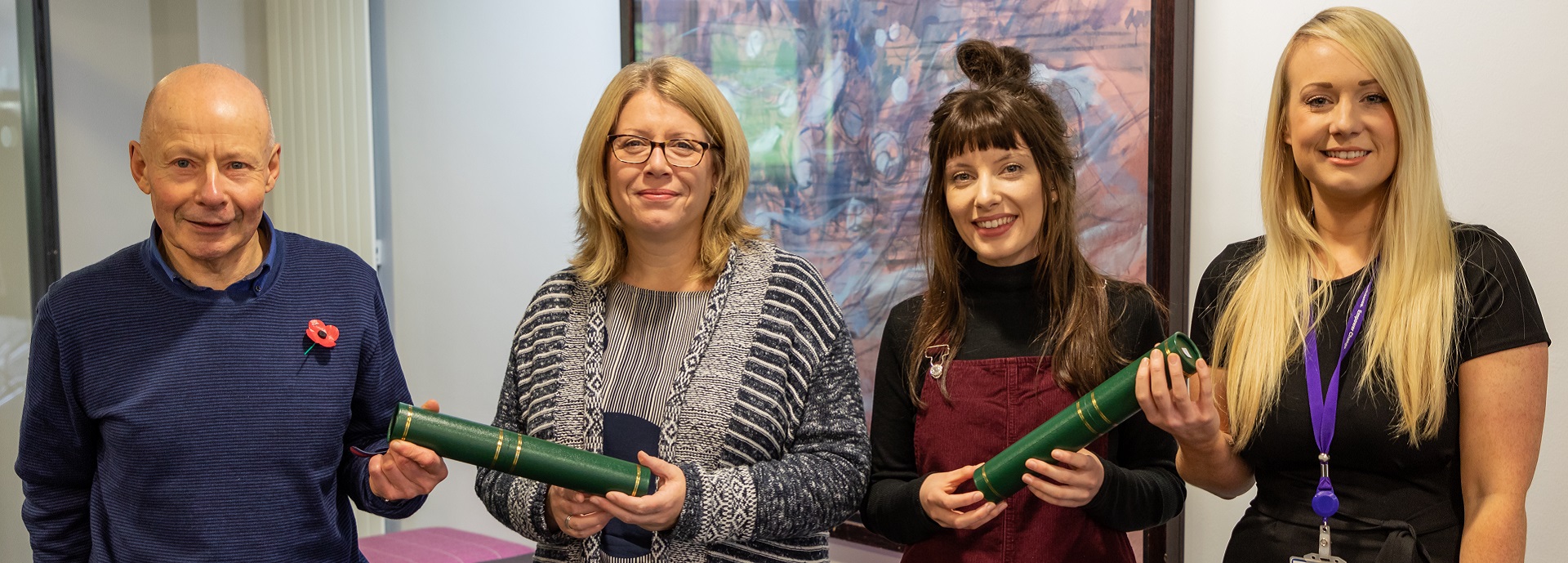 man and three women in a row with two university scrolls