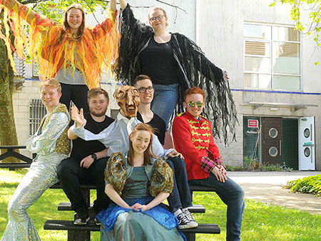 Group of actors wearing colourful costumes outside Macrobert Centre