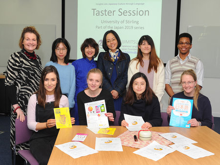 Teaching students and lecturers gathered around a table after language session 