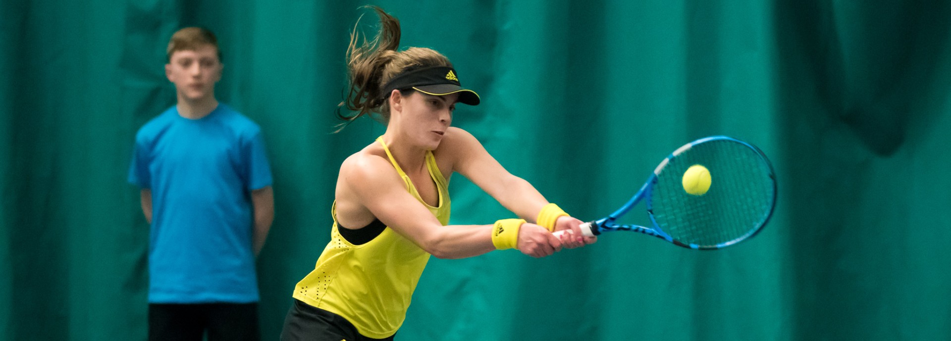 Tennis player Maia Lumsden hitting backhand shot