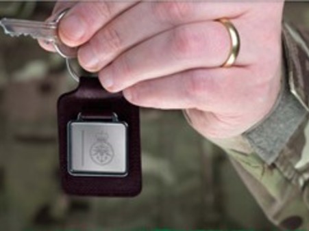 Hand of person in military uniform holding a key up