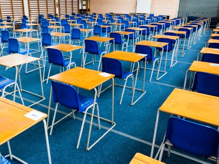 A school hall laid out with blue chairs and single desks