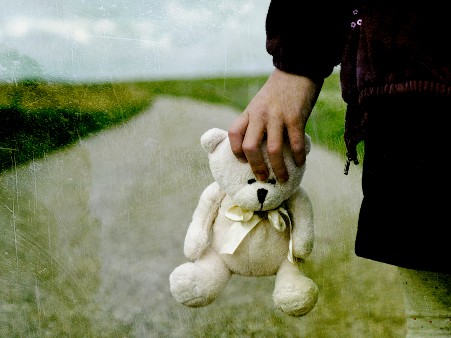 Child's hand holding a white teddy bear