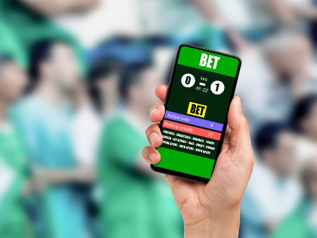 Close-up on man holding a cell phone while winning an online bet on a football game at stadium