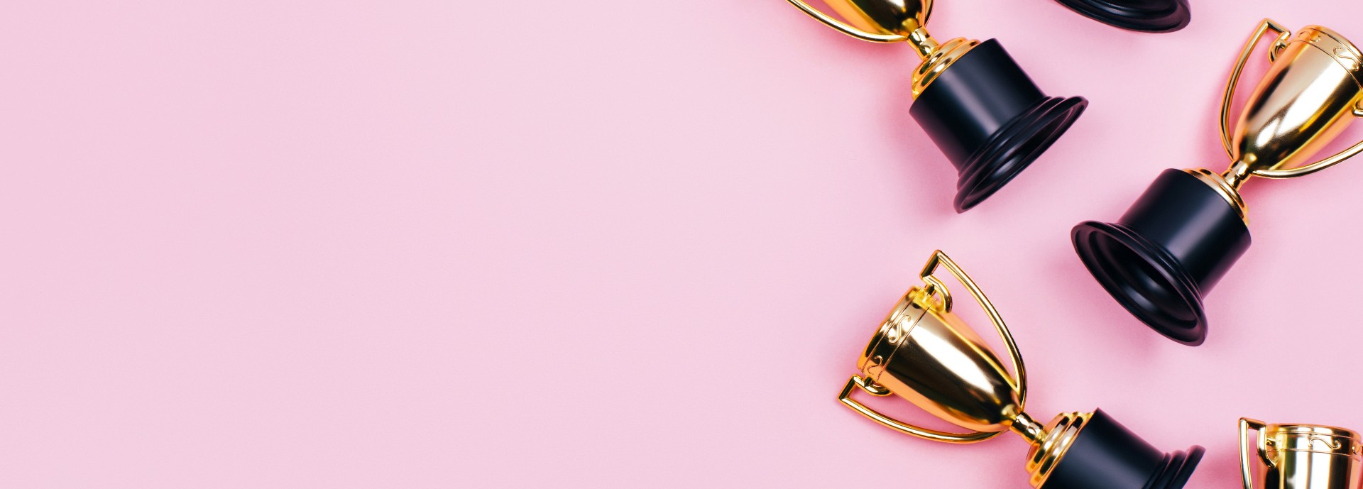 Winner cups on a pink background. Banner with a place for text. Flat lay style.