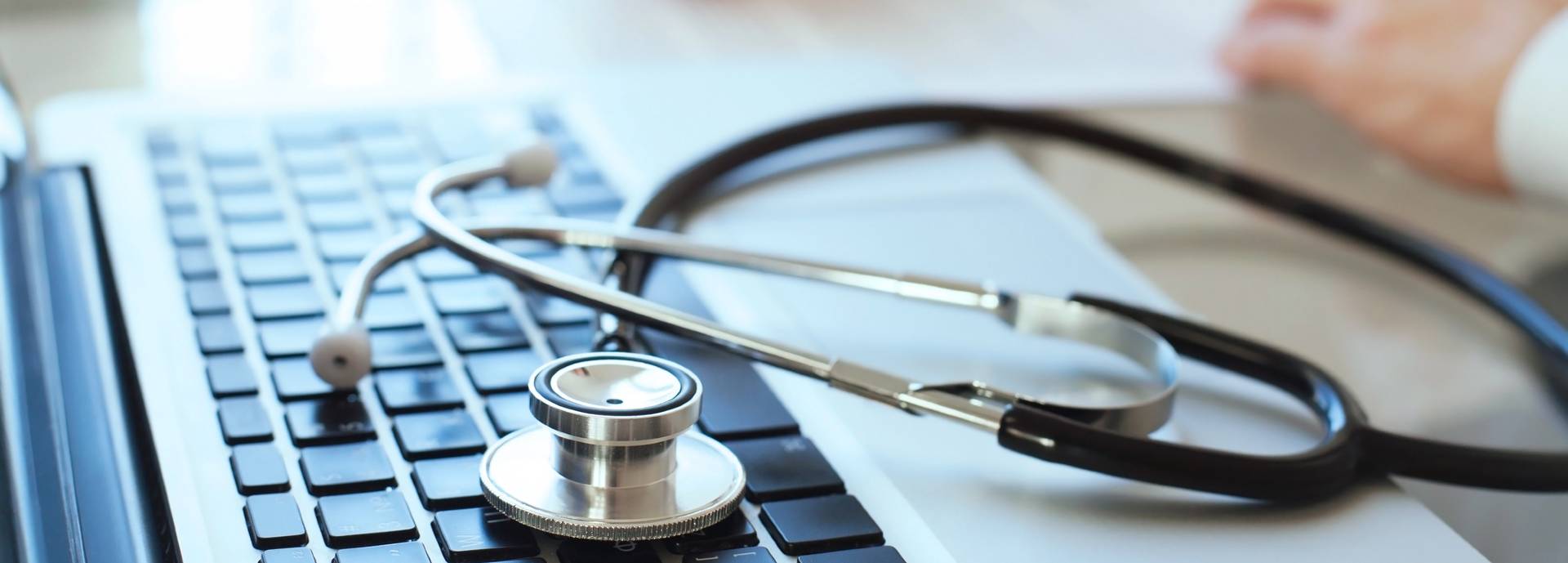 Stethoscope sits on top of a laptop keyboard in a GP's office