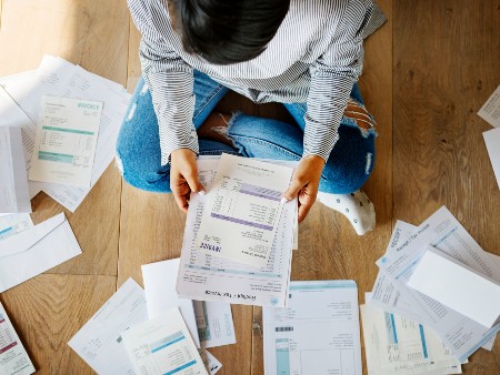 Person sitting on the floor surrounded by bills