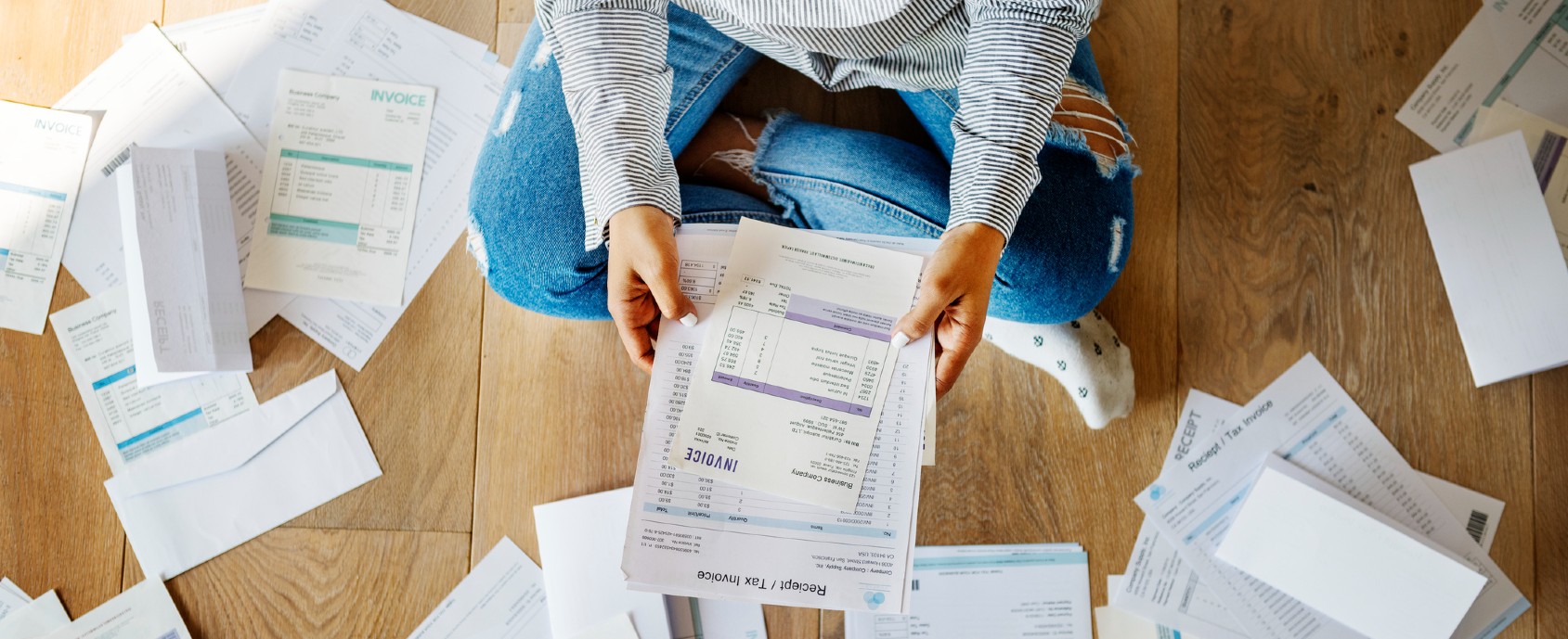 Person sitting on the floor surrounded by bills