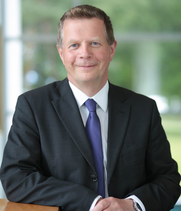 Professor Richard Oram wears a dark suit jacket, white shirt and blue tie.