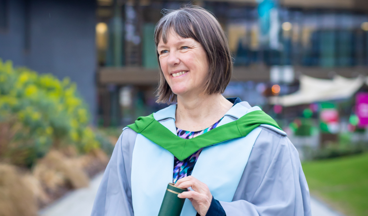 Kathleen Jamie wearing her graduation robes holding a University of Stirling scroll