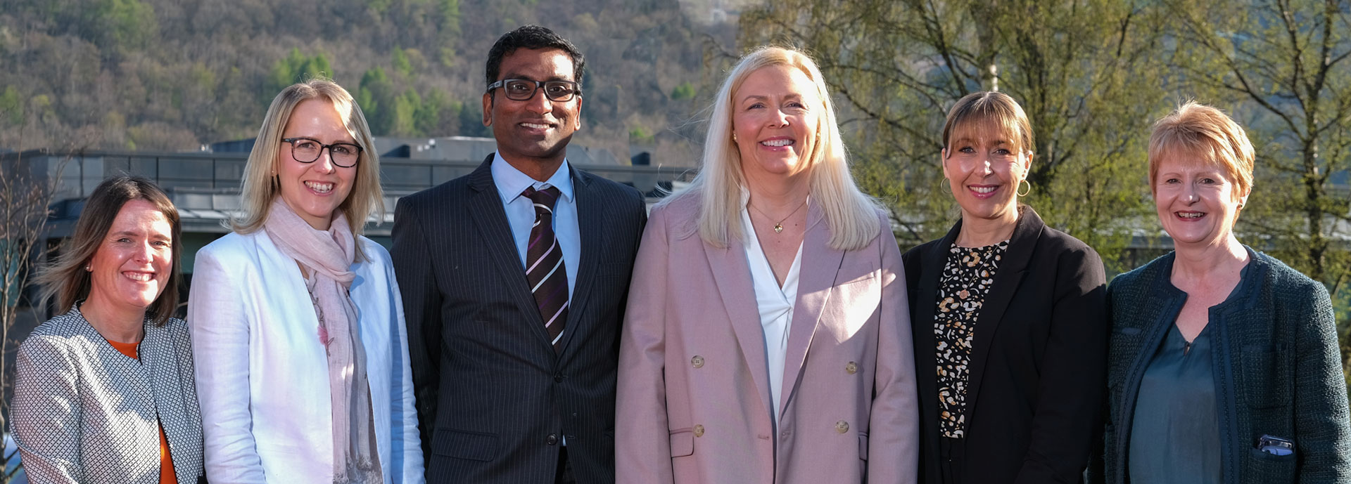 Six healthcare experts and academics stood next to each other outside