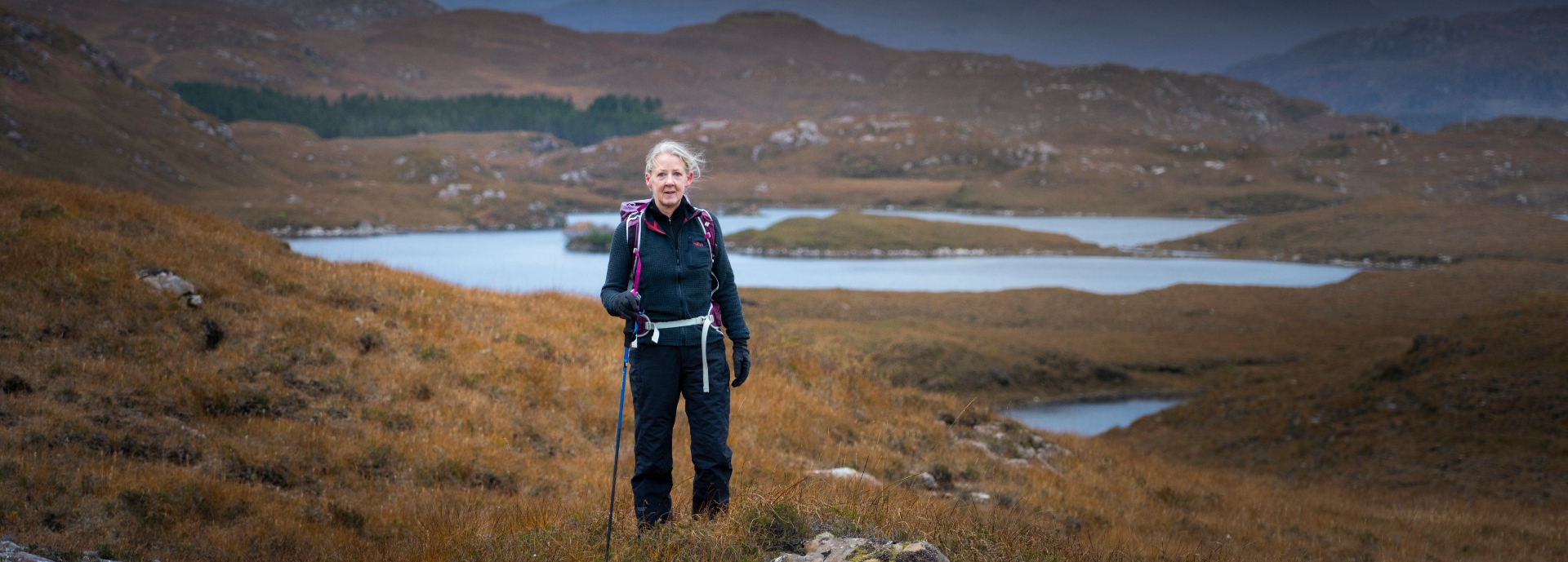 Helen Davies in hiking gear posing against a mountainous backdrop