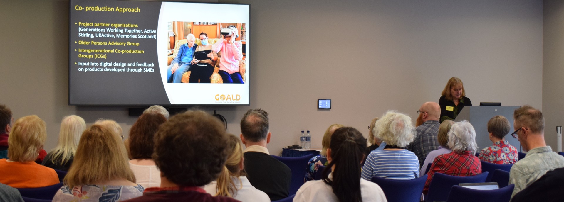 People seated in a conference room watching a presentation