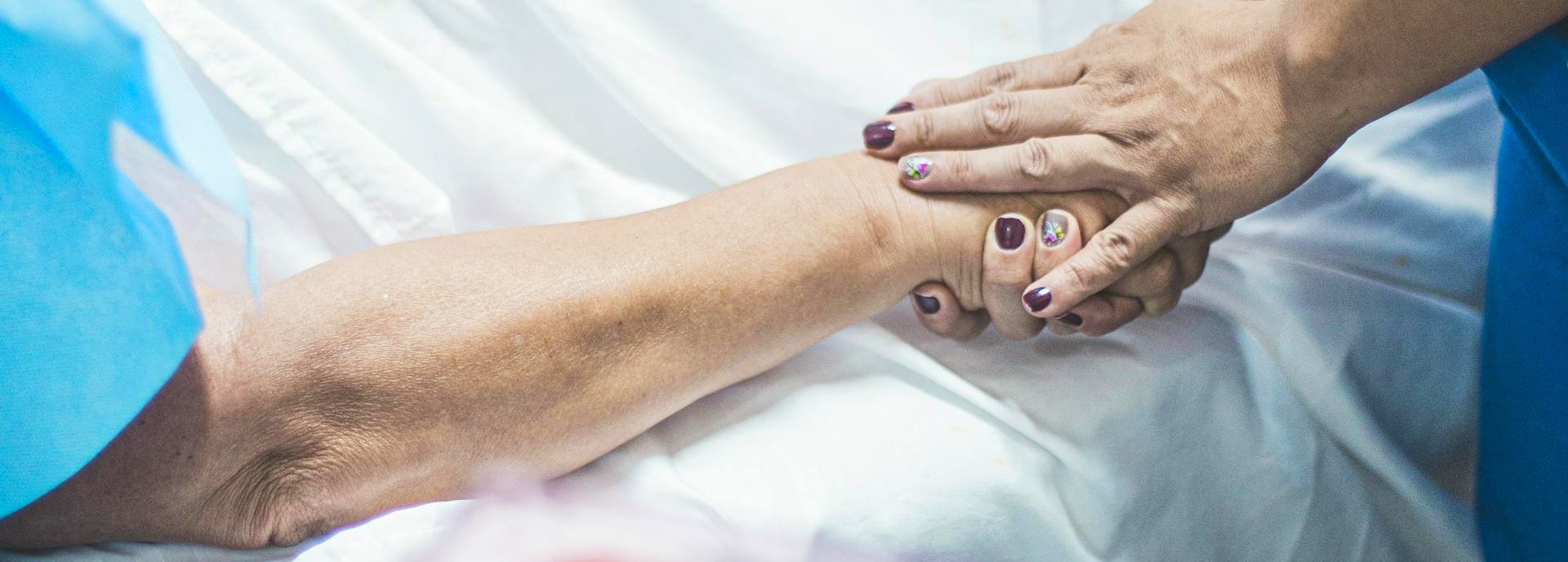 patient and nurse holding hands