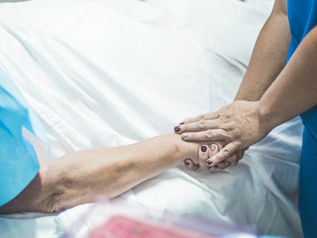 patient and nurse holding hands