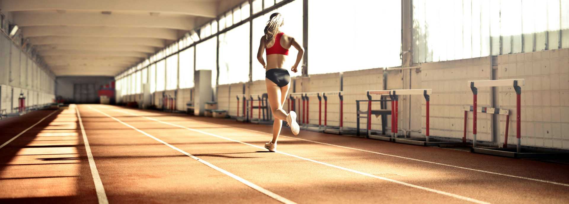 A female runner training on an indoor athletics track