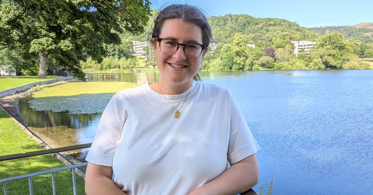 Sarah Weir of the University of Stirling smiles standing in front of Airthrey Loch