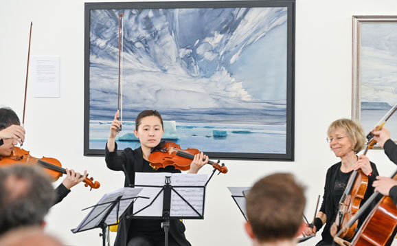 String musicians seated and playing in a gallery