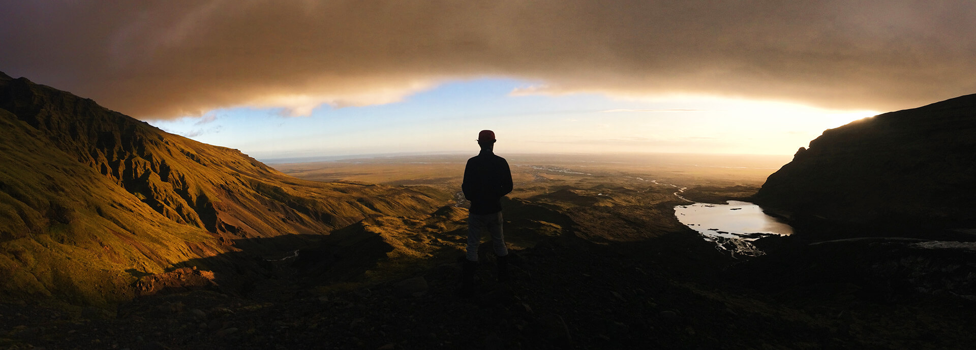 Man standing with back to camera looking over mountains and lakes