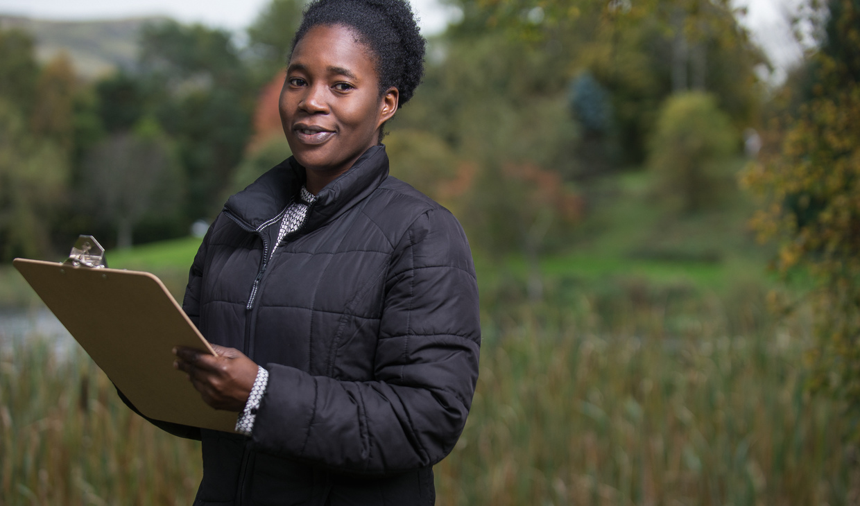 Environmental sciences student with clipboard standing by loch