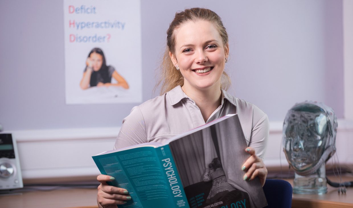 Postgraduate psychology student with head simulator and psychology poster