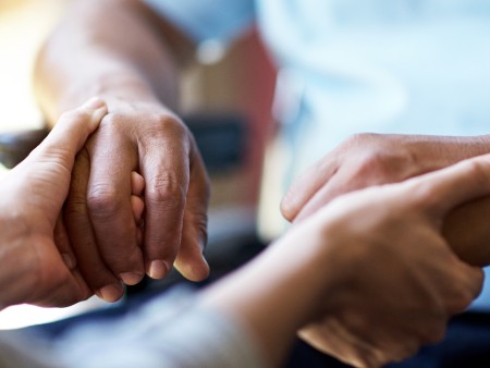 Closeup shot of a young woman holding a senior man's hands in comfort