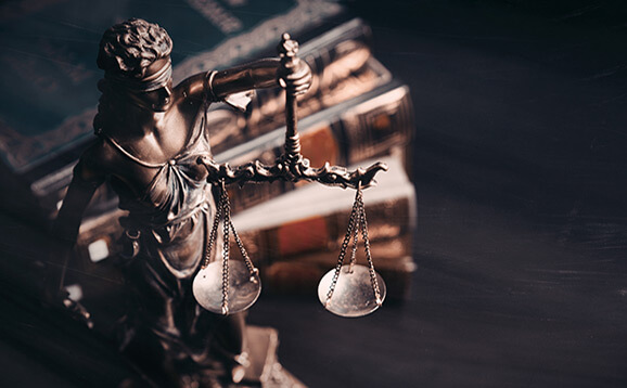 Lady of Justice statue and pile of old law books